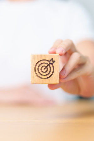 hand hold dartboard block with business goal, strategy, target, mission, action, objective, aim and success conceptの写真素材