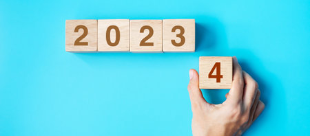 hand holding wooden cube block with 2024 text on blue background. Resolution, plan, review, goal, start and New Year holiday conceptsの写真素材