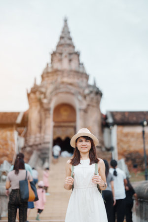 Young asian woman traveler in white dress with hat and bag traveling in Wat Phra That Lampang Luang, Tourist visit at Lampang, Thailand.. Asia Travel, Vacation and summer holiday conceptの写真素材