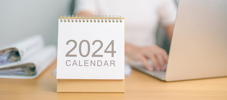 2024 Year Calendar on table with business woman using laptop computer. countdown, Happy New Year, Resolution, Goals, Plan,  Action, Mission and financial Conceptの写真素材