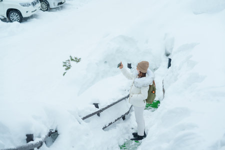 Woman tourist Visiting in Furano, Traveler in Sweater sightseeing Ningle Terrace Cottages with Snow...