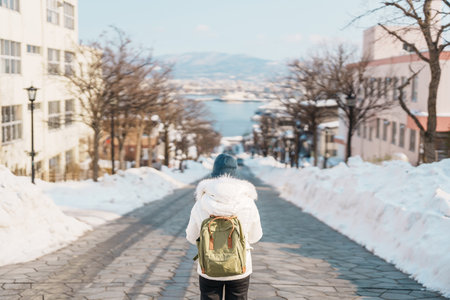Woman tourist Visiting in Hakodate, Traveler in Sweater sightseeing Hachiman Zaka Slope with Snow in winter. landmark and popular for attractions in Hokkaido, Japan. Travel and Vacation conceptの写真素材