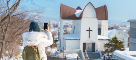 Woman tourist Visiting in Hakodate, Traveler in Sweater sightseeing Episcopal Church with Snow in winter. landmark and popular for attractions in Hokkaido, Japan. Travel and Vacation conceptの写真素材