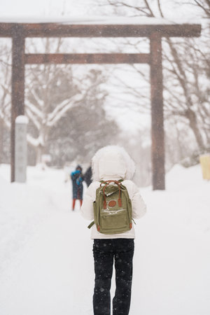 Woman tourist Visiting in Sapporo, Traveler in Sweater looking Hokkaido Shrine with Snow in winter season. landmark and popular for attractions in Hokkaido, Japan. Travel and Vacation conceptの写真素材