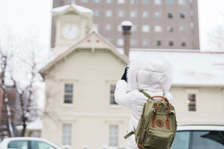 Woman tourist Visiting in Sapporo, Traveler in Sweater sightseeing Sapporo Clock tower with Snow in winter. landmark and popular for attractions in Hokkaido, Japan. Travel and Vacation conceptの写真素材