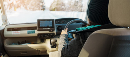 Happy Traveler driving car on snowy road, woman Tourist enjoying snow forest view from the car in winter season. Winter travel, Road trip, Exploring and Vacation conceptsの写真素材