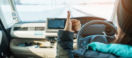 Happy Traveler driving car on snowy road and gesture finger up, woman Tourist enjoying snow forest...