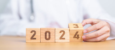 Doctor hand flipping 2023 to 2024 block. Happy New Year for Medical, Health care, Insurance and Wellness conceptsの写真素材