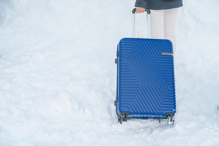 Luggage Suitcase with Snow, Tourist dragging Baggage during walking on snowy walkway. Winter travel, Journey and Vacation conceptの写真素材