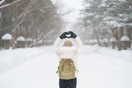Traveler with Sweater and backpack walking on snow covered forest in frosty weather. Winter Travel, Adventure, Exploring and Vacation conceptの写真素材