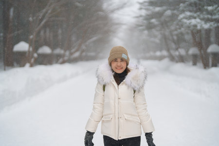 happy Traveler with Sweater and backpack walking on snow covered forest in frosty weather. Winter Travel, Adventure, Exploring and Vacation conceptの写真素材