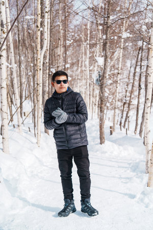 happy Traveler with Sweater walking on snow covered forest in frosty weather. Winter Travel, Adventure, Exploring and Vacation conceptの写真素材