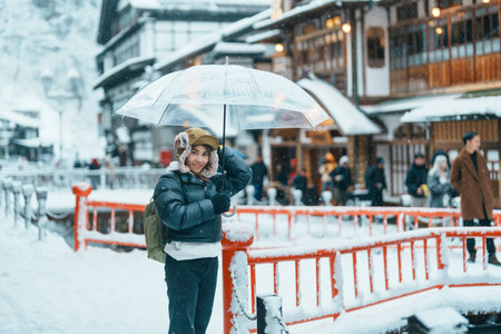 Woman tourist Visiting Ginzan Onsen in Yamagata, happy Traveler sightseeing Japanese Onsen village with Snow in winter season. landmark and popular for attraction in Japan. Travel and Vacation conceptの写真素材