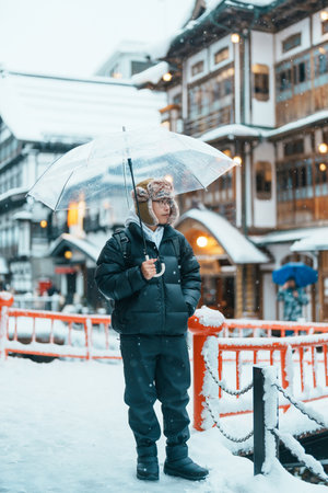 man tourist Visiting Ginzan Onsen in Yamagata, happy Traveler sightseeing Japanese Onsen village with Snow in winter season. landmark and popular for attraction in Japan. Travel and Vacation conceptの写真素材