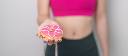 woman hand hold Donut with tape measure, choose stop eating sweet is Unhealthy ealthy food. Dieting control, Weight loss, Obesity, eating lifestyle and nutrition conceptsの写真素材