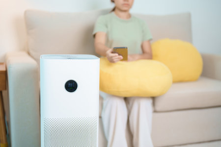 Air Purifier with woman relax and use smartphone on sofa. Purification system for filter and...