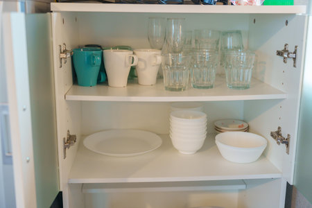 Set of dishes and glass in cabinet at apartment or Home. Kitchenware, dinnerware, lifestyle domestic...