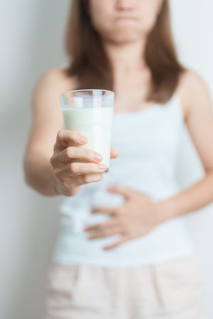 Lactose intolerance and Milk allergy concept. woman hold Milk glass and having abdominal cramps and pain when drink Cow Milk. Symptom stomach ache, Dairy intolerant, Nausea, Bloating, Gas and Diarrheaの写真素材