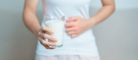 Lactose intolerance and Milk allergy concept. woman hold Milk glass and having abdominal cramps and pain when drink Cow Milk. Symptom stomach ache, Dairy intolerant, Nausea, Bloating, Gas and Diarrheaの写真素材