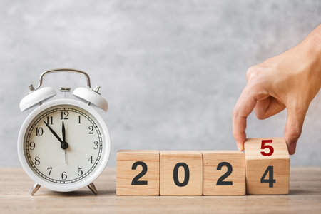 Happy New Year with vintage alarm clock and hand flipping 2024 change to 2025  block. Christmas, New Start, Resolution, countdown, Goals, Plan, Action and Motivation Conceptの写真素材