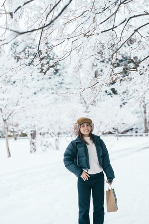 Traveler with Sweater and backpack walking on snow covered forest in frosty weather. Winter Travel, Adventure, Exploring and Vacation conceptの写真素材