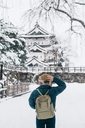 Woman tourist sightseeing Hirosaki Castle in winter, happy traveler travel Hirosaki city, Aomori Prefecture, Tohoku, Japan. Landmark and famous for tourist attraction. Japan travel and vacationの写真素材