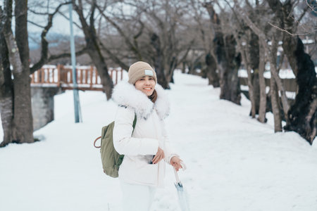Woman tourist sightseeing sakura trees with snow. Happy traveler travel near Hinokinai River riverbank in winter season locate in Kakunodate town, Semboku District, Akita Prefecture, Japanの写真素材