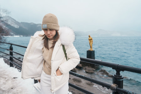 Woman tourist sightseeing golden Tatsuko statue and Lake Tazawa. Traveler travel in Semboku city, Akita Prefecture, Japan. Landmark for tourist attraction in Tohoku Region. Japan travel and vacationの写真素材