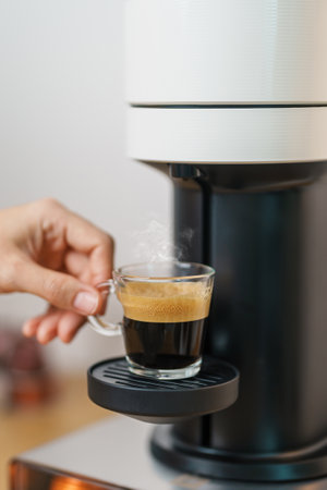hand making Espresso Coffee by Coffee Maker Machine with Capsule of roasted coffee bean on wood table bar. Daily beverage drink at Home, Apartment and Office conceptの写真素材