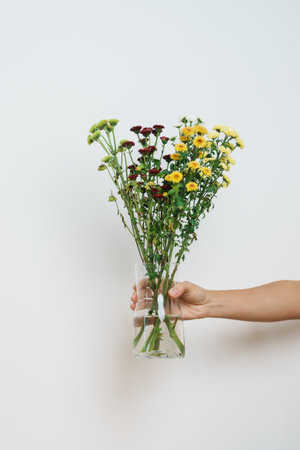 Woman hand hold Colorful flowers bouquet in mason jar on background. Happy day with fresh flowerの写真素材