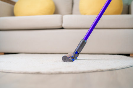 Woman cleaning Carpet with cordless Vacuum cleaner. Housewife using wireless Vacuum for big cleaning home. Housework, Housecleaning, Housekeeping, Removes dust, Domestic hygiene and daily routineの写真素材