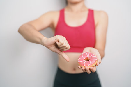 woman hand hold Donut with tape measure, choose stop eating sweet is Unhealthy ealthy food. Dieting control, Weight loss, Obesity, eating lifestyle and nutrition conceptsの写真素材