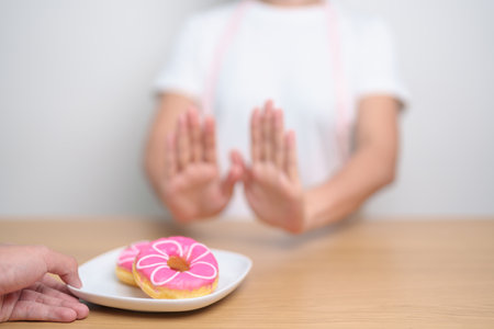 woman hand reject donut dessert, female refuse Unhealthy junk food. Dieting control, Weight loss, Obesity, eating lifestyle and nutrition conceptsの写真素材