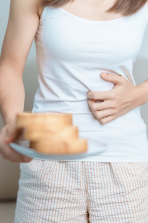 Gluten intolerance, Gluten free and celiac disease or wheat allergy concept. woman hold Bread and having abdominal pain after eat gluten. stomach ache, Nausea, Bloating, Gas, Diarrhea and Skin rashの写真素材