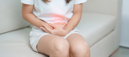 woman having abdomen ache due to Stomach pain, digestion with constipation or Diarrhea from food poisoning, female problem and Endometriosis, Hysterectomy, Stomachache and Menstrual on sofa at homeの写真素材