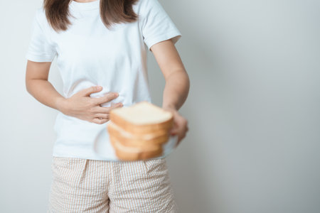 Gluten intolerance, Gluten free and celiac disease or wheat allergy concept. woman hold Bread and having abdominal pain after eat gluten. stomach ache, Nausea, Bloating, Gas, Diarrhea and Skin rashの写真素材