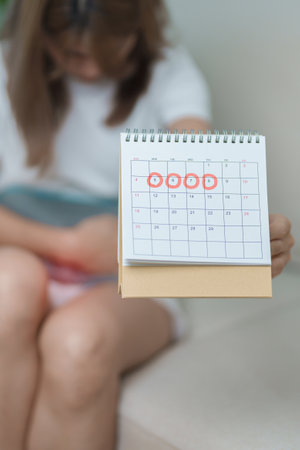Menstruation period cycle of monthly and Stomachache concepts. woman having abdomen pain with hot water bottle and calendar, illness female suffer from premenstrual ache and body Health problemの写真素材