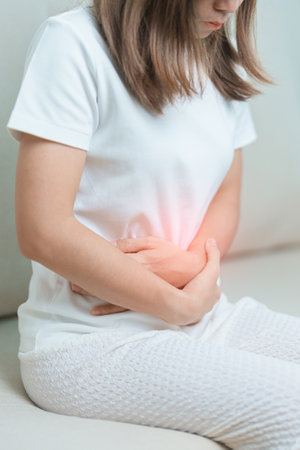 woman having abdomen ache due to Stomach pain, digestion with constipation or Diarrhea from food poisoning, female problem and Endometriosis, Hysterectomy, Stomachache and Menstrual on sofa at homeの写真素材