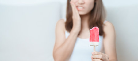 Teeth Sensitive to Cold concept. woman hold Ice cream and having toothache and pain after eat. Tooth Decay or Gum Disease, Grinding Teeth and Stress, Exposed Nerve Roots, Crack and Receding Gumsの写真素材