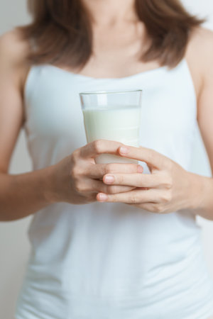 Milk drink and Daily Routine concept. Young woman Drinking milk with high calcium and nutrition at home, woman holding soy milk on glass with protein. Healthy, wellness and happy lifestyleの写真素材