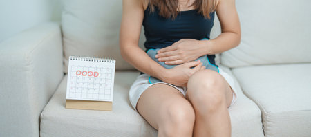 Menstruation period cycle of monthly and Stomachache concepts. woman having abdomen pain with hot water bottle and calendar, illness female suffer from premenstrual ache and body Health problemの写真素材
