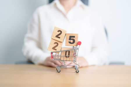 Happy new year with 2025 block in shopping trolley cart on table. E commerce, online shopping, finance, consumer economy and celebration conceptsの写真素材
