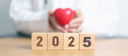 Happy New Year 2025 with doctor holding red heart shape on table. health care, Insurance, donation,...