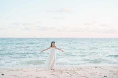 Happy traveler woman in white dress enjoy beautiful sea view, young woman standing on sand and looking ocean at tropical beach. Freedom, relaxing, vacation holiday and summer travel conceptの写真素材