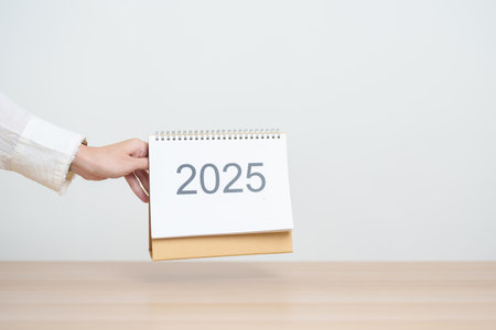 Business woman hand change 2025 Year Calendar on table in office background. countdown, Happy New Year, Resolution, Year End and New Start and Goals Plan Action Conceptの写真素材