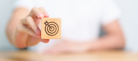 hand hold dartboard block with business goal, strategy, target, mission, action, objective, aim and success conceptの写真素材
