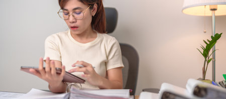 Asian woman working with tablet, female businesswoman reading report and sign contract with documents folder stack at home or office late night. Overworked, work hard and business conceptの写真素材