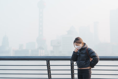 young Asian woman wearing respiratory mask protect and filter pm or particulate matter against bad Air Pollution in Shanghai City, China. Air Quality Index, AQI, Unhealthy, healthcare conceptの写真素材