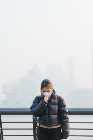 young Asian woman wearing respiratory mask protect and filter pm or particulate matter against bad Air Pollution in Shanghai City, China. Air Quality Index, AQI, Unhealthy, healthcare conceptの写真素材