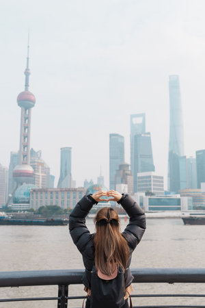 woman traveler visiting in Shanghai, China. Female Tourist with backpack sightseeing Shanghai view of Lujiazui in The Bund of Shanghai. landmark and popular for tourism attractions. Vacation conceptの写真素材
